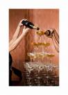 Plakat przedstawiający nalewanego szampana do kieliszków.