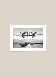 Czarno-biały poziomy plakat przedstawiający startujący samolot.