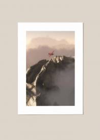 Plakat, fotografia przedstawiająca czerwoną awionetkę lecącą nad górami.