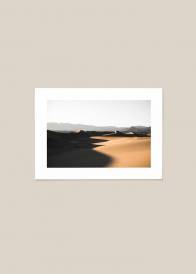 Plakat przedstawiający oświetlone piaski pustyni.