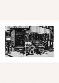 Czarno-biały plakat przedstawiający uliczną kawiarnię w Paryżu.