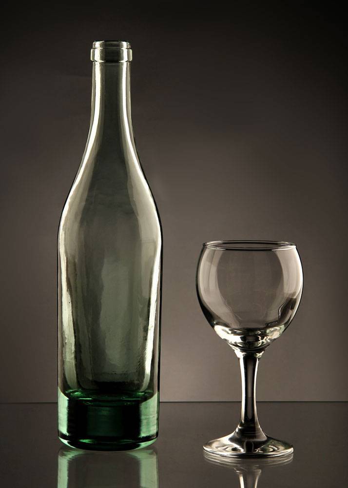Plakat fotograficzny przedstawiający zieloną butelkę po winie i kieliszek na ciemnym tle.