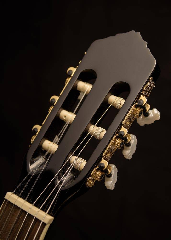 Plakat przedstawiający gryf gitary na czarnym tle.