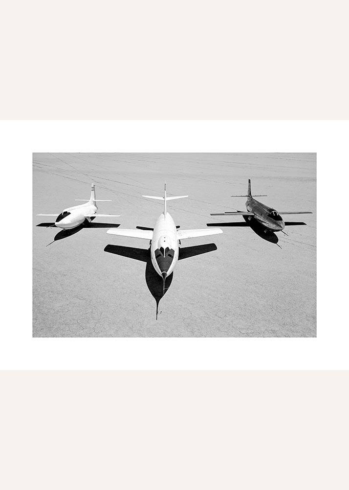 Plakat przedstawiający trzy samoloty myśliwskie na pasie startowym.